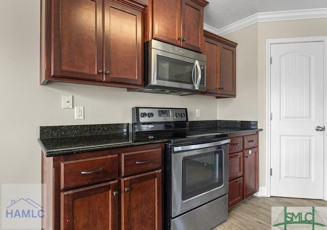 kitchen with stainless steel appliances, dark stone counters, crown molding, and light wood-style flooring