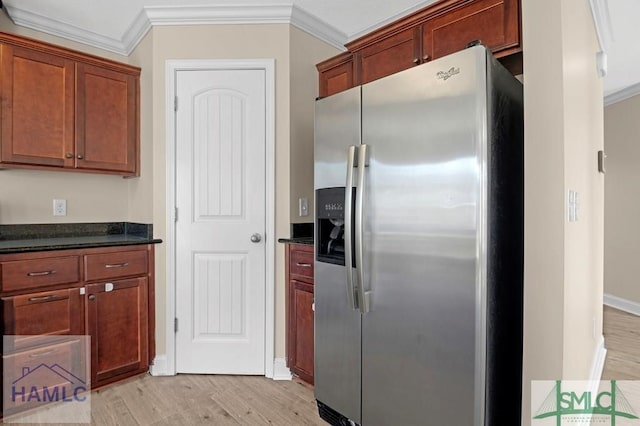 kitchen with light wood-type flooring, ornamental molding, stainless steel refrigerator with ice dispenser, and dark stone countertops