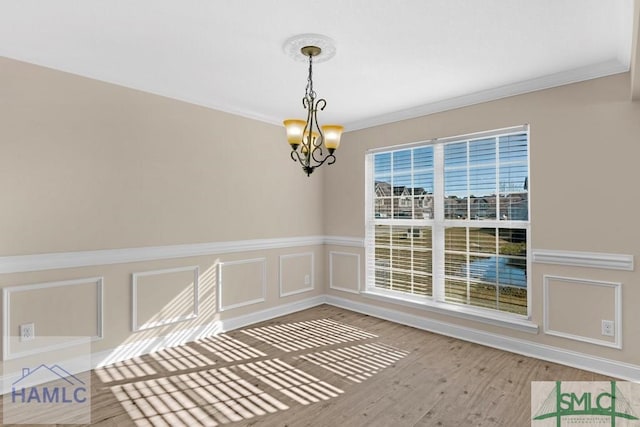 interior space featuring ornamental molding, a notable chandelier, a decorative wall, and wood finished floors