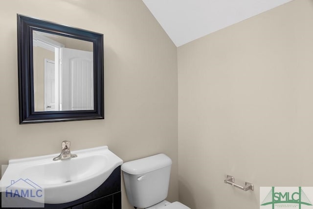 half bath with toilet, vaulted ceiling, and vanity