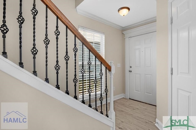 entryway with light wood-style floors, baseboards, stairway, and crown molding