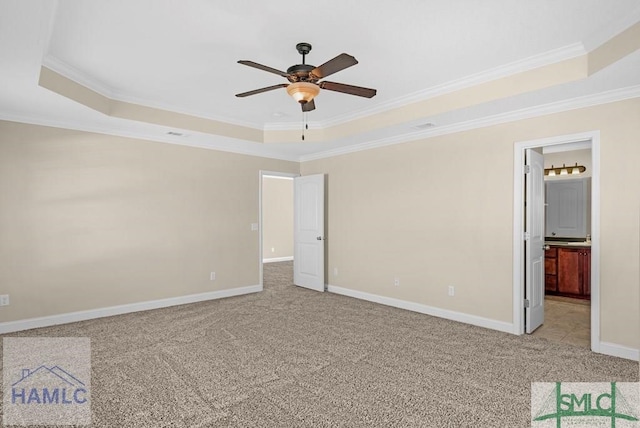 unfurnished bedroom with a raised ceiling, light colored carpet, crown molding, and baseboards