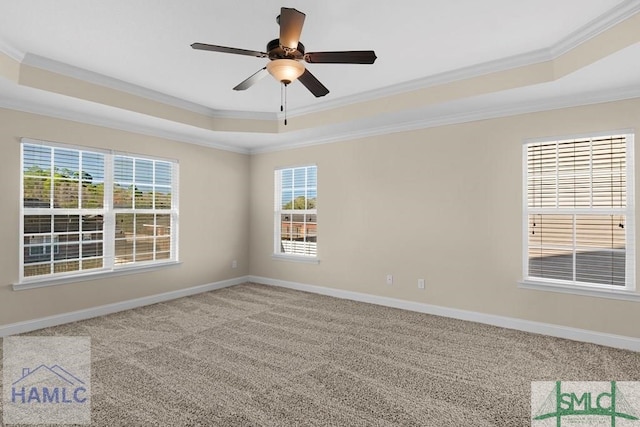 carpeted empty room featuring crown molding, ceiling fan, a raised ceiling, and baseboards