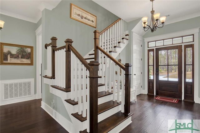 entryway featuring visible vents, baseboards, ornamental molding, hardwood / wood-style floors, and an inviting chandelier