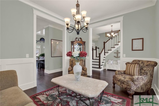 living area with a notable chandelier, crown molding, stairway, wainscoting, and wood finished floors