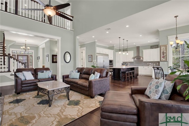 living room featuring a wealth of natural light, dark wood-style floors, ornamental molding, and a notable chandelier