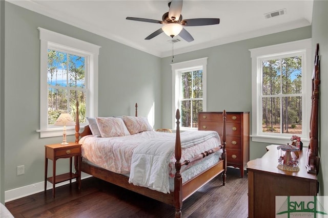 bedroom featuring dark wood-style floors, visible vents, crown molding, and baseboards