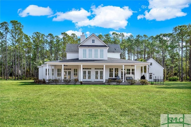 view of front of house with a ceiling fan, a front yard, french doors, and a chimney