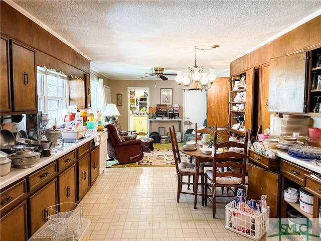 kitchen featuring ornamental molding, light countertops, a textured ceiling, and ceiling fan with notable chandelier