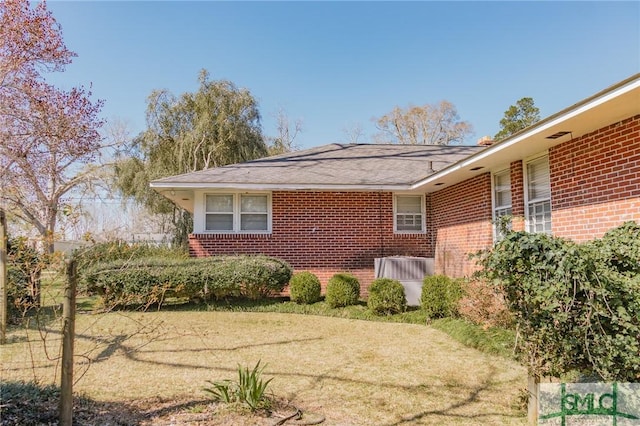 view of side of property with a lawn and brick siding