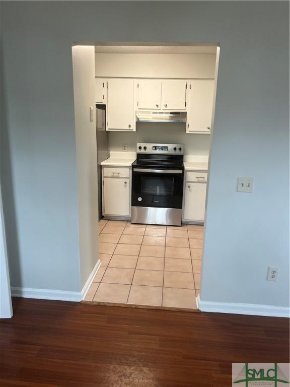 kitchen featuring stainless steel electric stove, light countertops, light wood-style floors, white cabinets, and under cabinet range hood