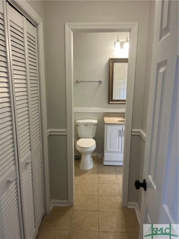 bathroom with toilet, tile patterned flooring, a closet, and vanity