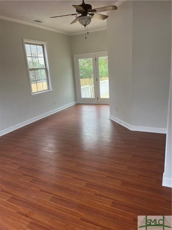 unfurnished room featuring visible vents, ornamental molding, dark wood-type flooring, and a wealth of natural light