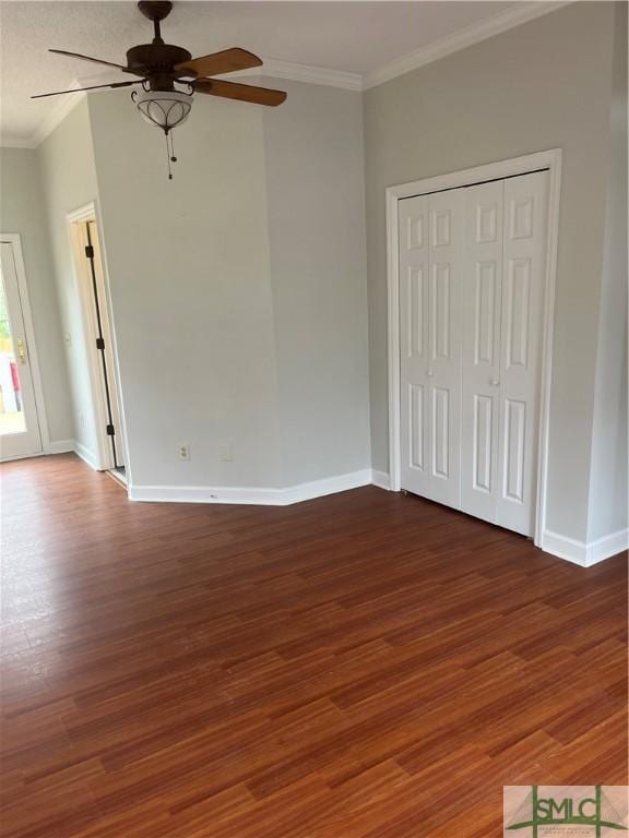 unfurnished bedroom featuring dark wood-style floors, baseboards, a ceiling fan, and crown molding