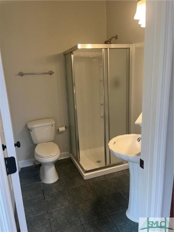 bathroom featuring a stall shower, baseboards, tile patterned flooring, and toilet