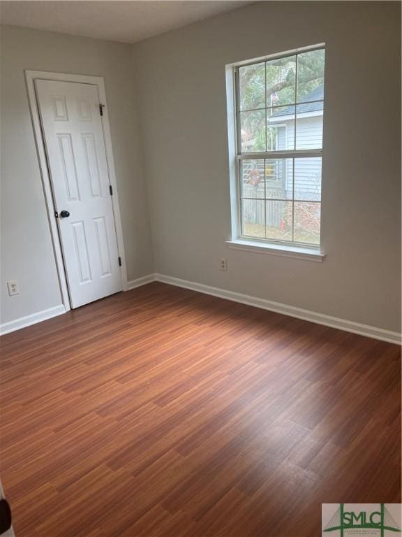 empty room featuring baseboards and dark wood-style flooring