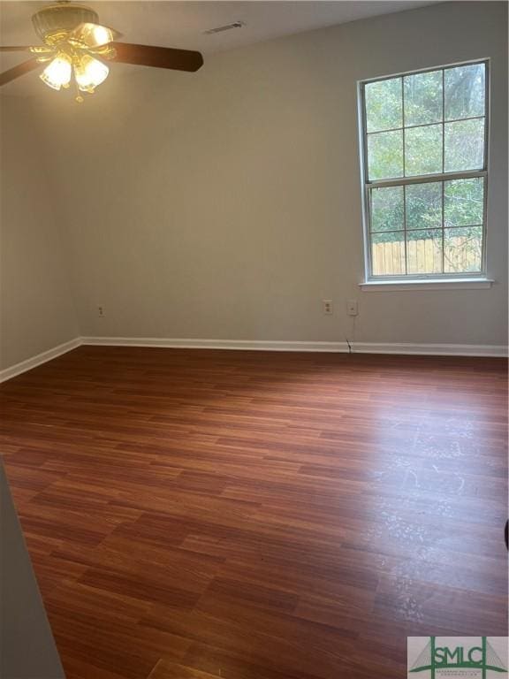 empty room with baseboards, visible vents, and dark wood-style flooring