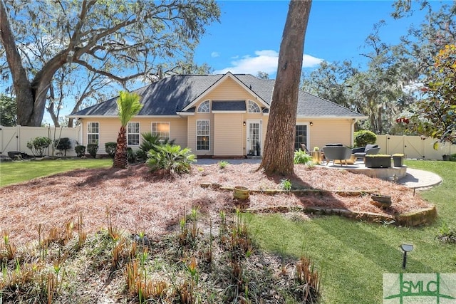 rear view of property featuring a patio, a lawn, and a fenced backyard