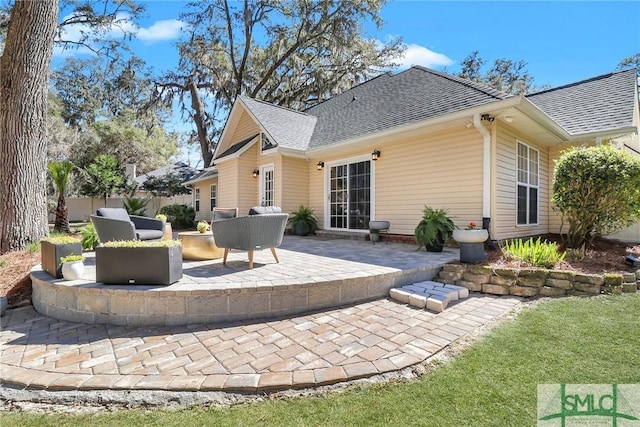 back of house with a shingled roof, fence, and a patio