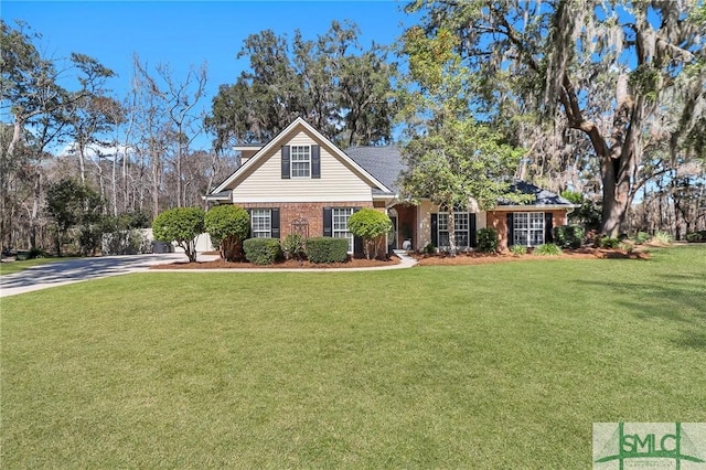 view of front of property with a front yard, brick siding, and driveway