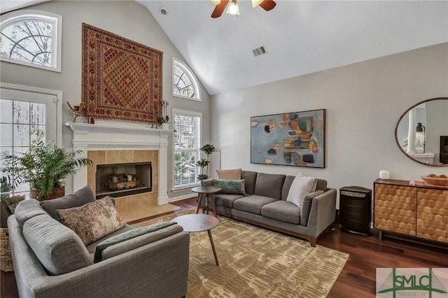 living room featuring high vaulted ceiling, a fireplace, wood finished floors, visible vents, and a ceiling fan