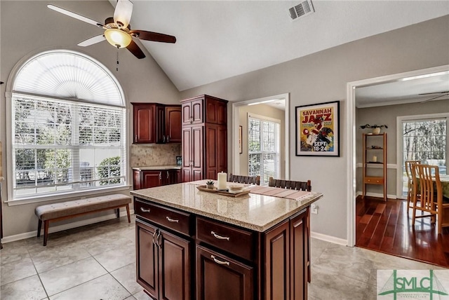 kitchen featuring a healthy amount of sunlight, visible vents, a ceiling fan, and a center island