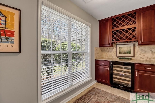 bar featuring a bar, wine cooler, backsplash, and baseboards