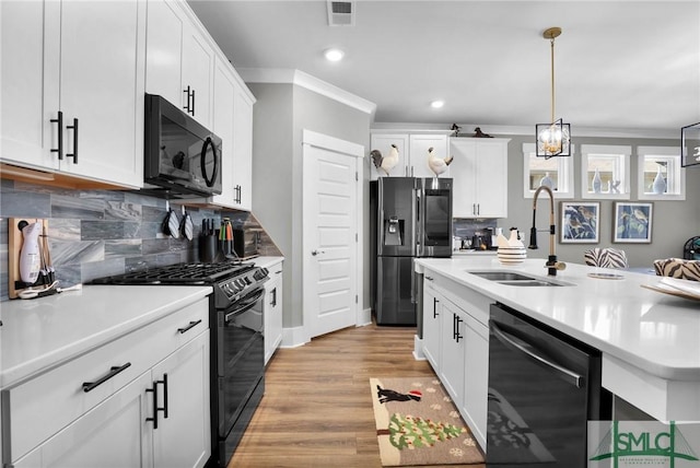 kitchen with visible vents, light wood-style flooring, light countertops, black appliances, and a sink