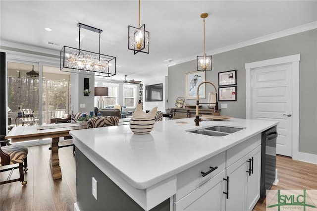 kitchen with ceiling fan, a sink, ornamental molding, light wood-type flooring, and dishwasher