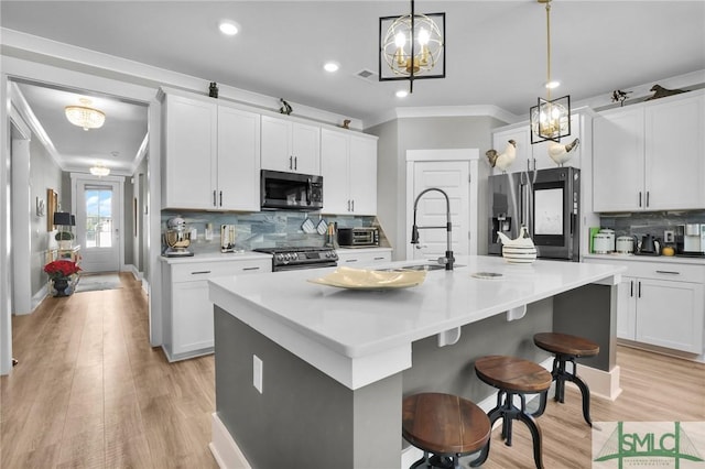 kitchen featuring stainless steel appliances, ornamental molding, an island with sink, and a sink