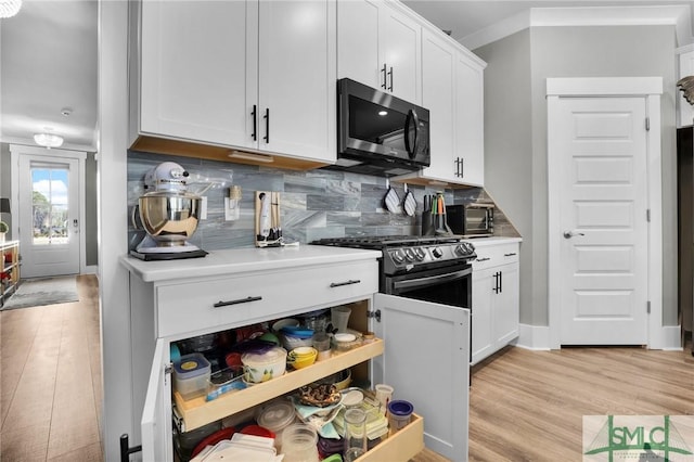 kitchen with tasteful backsplash, light countertops, appliances with stainless steel finishes, white cabinets, and light wood-type flooring