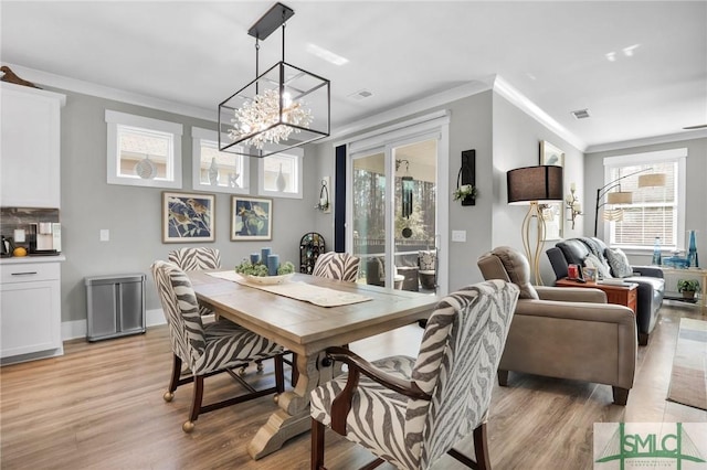 dining area with crown molding, visible vents, an inviting chandelier, light wood-style floors, and baseboards