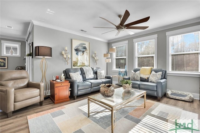 living room with light wood finished floors, ceiling fan, visible vents, and ornamental molding