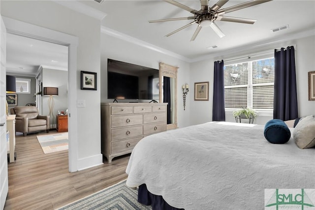 bedroom with baseboards, visible vents, a ceiling fan, ornamental molding, and light wood-type flooring