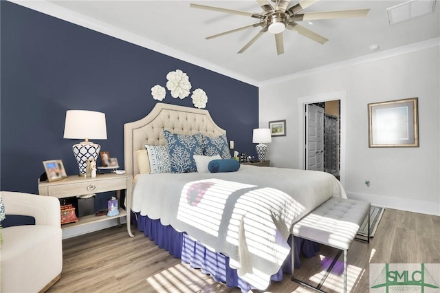 bedroom with ornamental molding, visible vents, baseboards, and wood finished floors