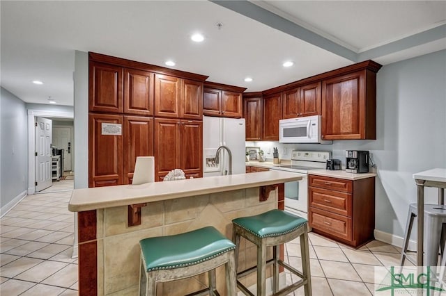 kitchen with light tile patterned floors, white appliances, recessed lighting, and light countertops