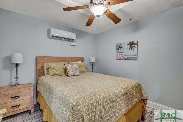 bedroom with a wall mounted air conditioner, baseboards, wood finished floors, and a ceiling fan