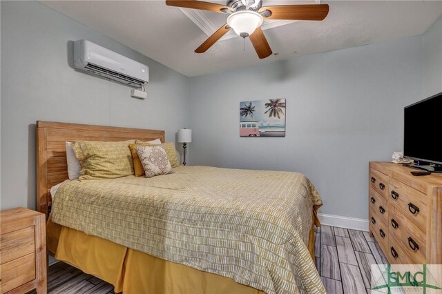 bedroom with an AC wall unit, a ceiling fan, baseboards, and wood finished floors