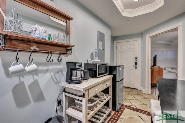 interior space featuring light tile patterned floors, a tray ceiling, electric panel, appliances with stainless steel finishes, and crown molding