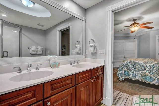 bathroom with ceiling fan, double vanity, wood finished floors, and a sink