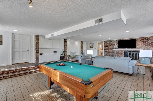 rec room featuring a brick fireplace, visible vents, a textured ceiling, and light tile patterned flooring