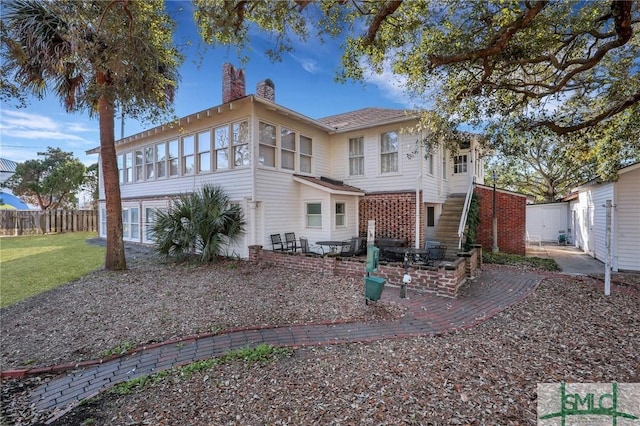 rear view of property with a lawn, fence, a chimney, and a patio