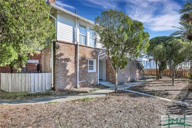 view of property exterior with brick siding and fence