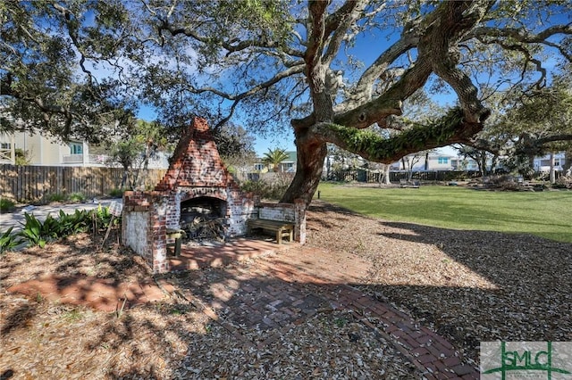 view of yard with an outdoor brick fireplace, a patio area, and fence