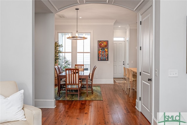 dining room featuring baseboards, dark wood-type flooring, a chandelier, and crown molding