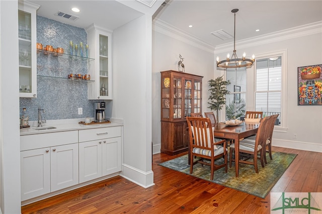 dining space featuring crown molding, visible vents, an inviting chandelier, baseboards, and hardwood / wood-style flooring