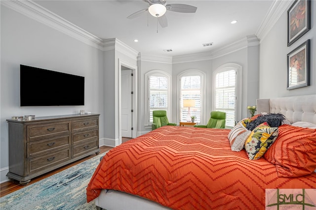 bedroom featuring ceiling fan, wood finished floors, visible vents, baseboards, and crown molding