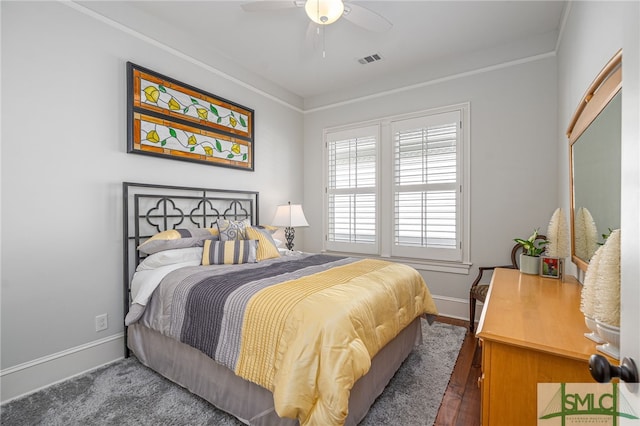 bedroom featuring wood finished floors, a ceiling fan, visible vents, baseboards, and crown molding