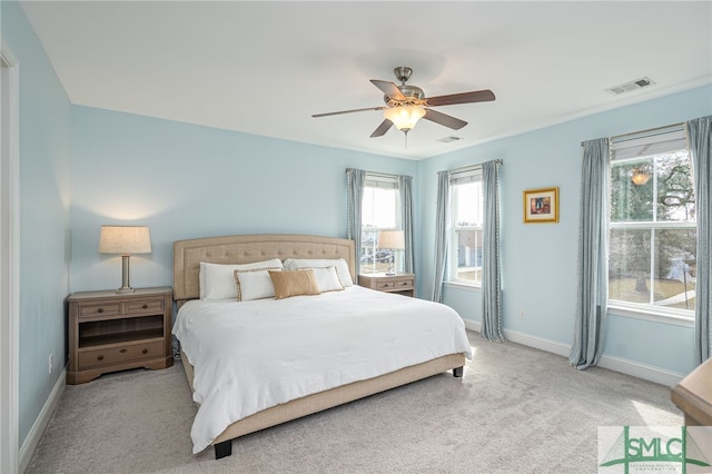 bedroom featuring a ceiling fan, visible vents, light carpet, and baseboards