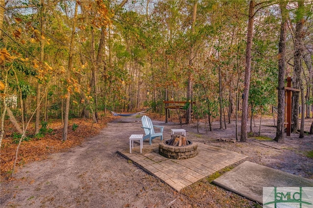 view of patio / terrace featuring a forest view and an outdoor fire pit